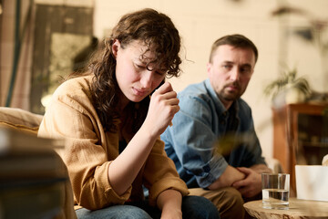 Young woman sitting on sofa in psychologist office and crying, she worrying about her problems with...