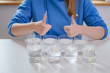 8 szklanek z wodą i kobieta podnosząca kciuki w górę  - obrazy, fototapety, plakaty