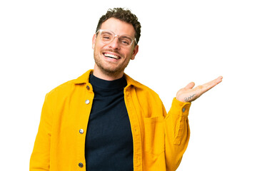 Brazilian man over isolated chroma key background holding copyspace imaginary on the palm to insert...
