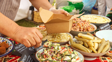 A man at a traditional Palestinian food stall prepares a snack box for a customer.