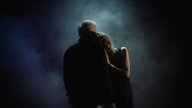 aged man hugging a woman. Loving couple on a dark background. old man and young woman