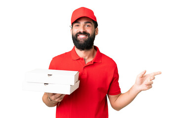 Pizza delivery man with work uniform picking up pizza boxes over isolated chroma key background pointing finger to the side