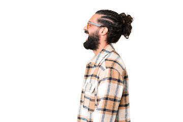 Young man with beard over isolated chroma key background laughing in lateral position