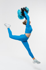 The concept of performance at competitions. A female cheerleader in a blue suit jumps up on a white...