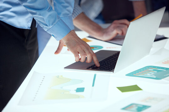 Closeup businessmen hands during business meeting in technology research laboratory. Co-workers gathered around illuminated conference table.