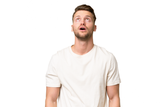 Young blonde caucasian man over isolated background looking up and with surprised expression