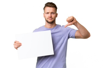 Young blonde caucasian man over isolated background holding an empty placard and doing bad signal