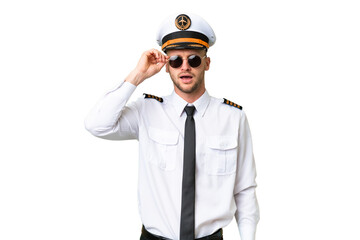 Airplane pilot man over isolated background with glasses and surprised