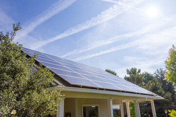 Modern house with blue solar panels on the roof. End of the day, sunset.