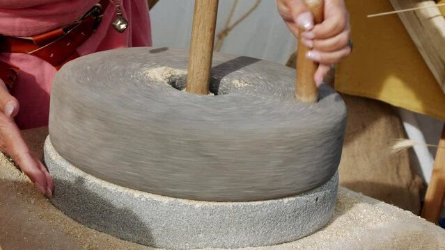 hand using a large authentic millstone, medieval utensil for grinding grains
