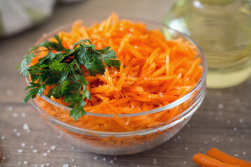 Carrot salad in salad bowl on the table. Carrots and greens.