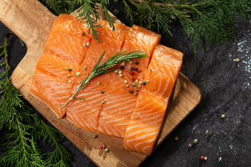 Salmon. Fresh raw salmon fish fillet with cooking ingredients, herbs and lemon on black background