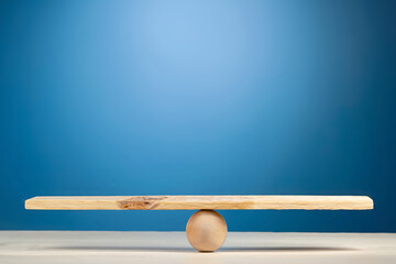 Stability, balance and equality concept. Wooden scale on blue background.