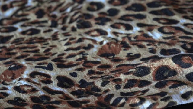 Macro shot with movement of fabric with leopard print, extreme close up of cloth texture. Abstract fabric surface. . High quality 4k footage