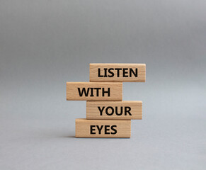 Listen with your eyes symbol. Concept word Listen with your eyes on wooden blocks. Beautiful grey background. Business and Listen with your eyes concept. Copy space