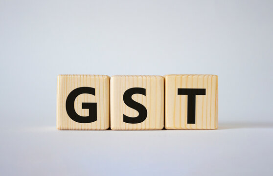 GST - Goods and Services Tax symbol. Concept word GST on wooden cubes. Beautiful white background. Business and GST concept. Copy space.