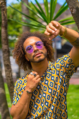 Portrait of afro haired man on summer vacation next to some palm trees by the beach. Travel and tourism concept