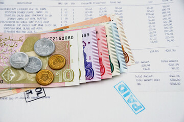 Currency notes in Pakistani Rupees with a paid invoice.