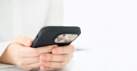 Business and technology concept. Pensive casual business man, freelancer, programmer using smart mobile phone while working on laptop computer thinking about her project in modern office, close up