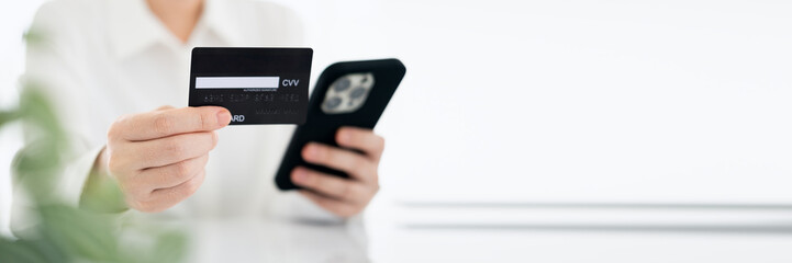 Close up female hands holding credit card and smartphone, young woman paying online, using banking service, entering information, shopping, ordering in internet store, doing secure payment