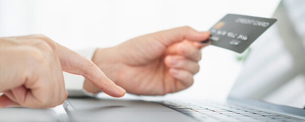 Woman hand holding credit card and using laptop at home, online shopping and paying bills, Payment method.