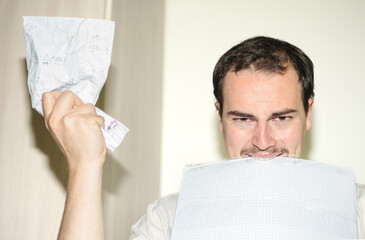 Man raising his hands and biting papers angry from stress of work