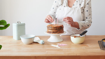 woman decorating birthday cake with candles