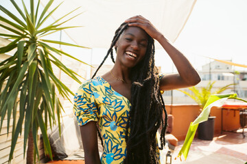 Cheerful black woman with dreadlocks on terrace