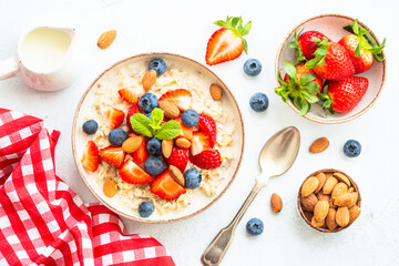 Oatmeal porrige with fresh berries and nuts. Healthy breakfast, top view.
