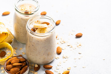 Almond banana smoothie with oat flakes in glass jars.