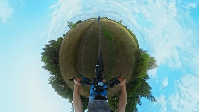 Friends ride MTB bicycles along path in field. 360 degrees action camera shot with tiny planet projection, Fisheye lens. Trip journey with cross-country mountain bikes. Sports recreations
