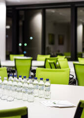 a conference room interior filled with lots of green chairs and tables ready for a corporate meeting
