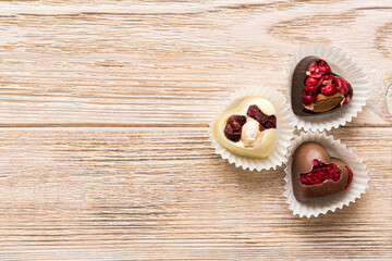 chocolate sweets in the form of a heart with fruits and nuts on a colored background. top view with space for text, holiday concept
