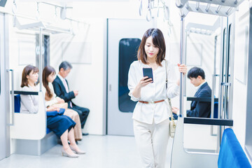 電車でスマホを使う若い女性