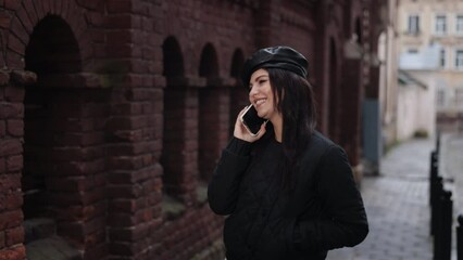 phone communication, talkative walker, street walk. As she walks down road, young woman is absorbed in phone discussion.