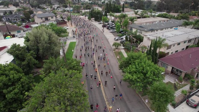 Drone establishing shot of big running event and foot race of Rock 'n' Roll marathon series in San Diego, California neighborhood during a summer morning