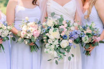 Bride and bridesmaids in lavender dresses in a summertime wedding bouquets with white, pink, and purple flowers and green leaves.