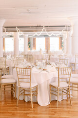 A wedding reception is decorated simply with hanging lights, a formal table decorated with white tablecloth and gold tables 