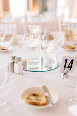 A dinner reception table is decorated with floating candles in the center and served toast as an appetizer. 