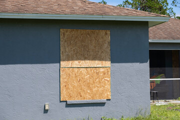 Boarded up windows with plywood storm shutters for hurricane protection of residential house....