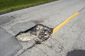Dangerous pothole on american road surface. Ruined driveway in urgent need of repair