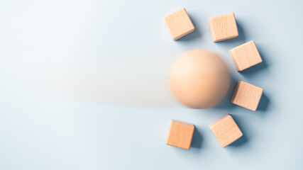 Motion blur of rolling sphere ball crashing blank wooden cube wall blocks high speed blue...