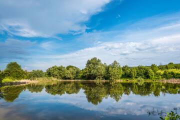Scenic view of trees reflected to lake water at countryside in Europe against summer dramatic sky 