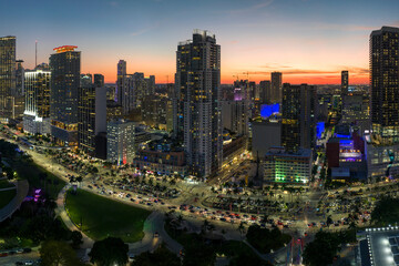 Fototapeta premium View from above of brightly illuminated skyscraper buildings and street traffic in downtown district of Miami Brickell in Florida, USA at night. American megapolis with business financial district