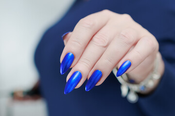 Woman's beautiful hand with long nails and bright blue manicure