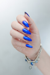 Woman's beautiful hand with long nails and bright blue manicure