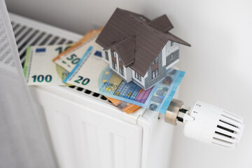 New thermostat with Euro cash on a radiator heating at home. Expensive heating costs symbolic image.