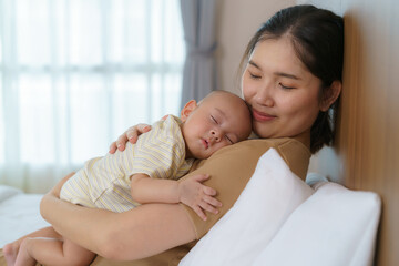 The Asian mother hugged her young son so that she could have a good sleep in the bedroom at home,...