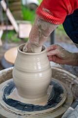 Making of mud pot on potters wheel during workshop outdoor