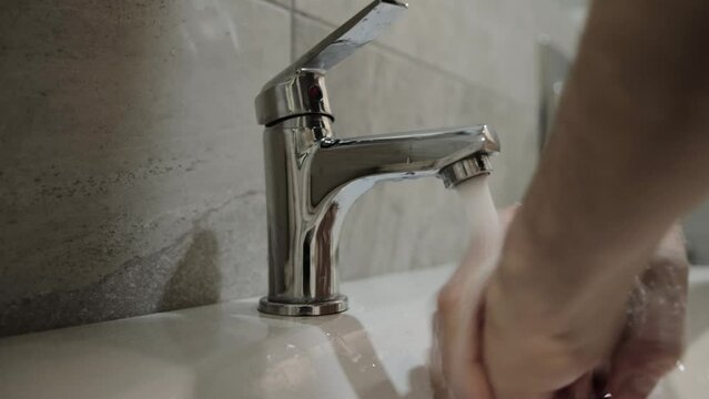 Washing hands under the tap in the bathroom after using the toilet. Hand hygiene, protection against salmonella and other diseases, dirty hands, close-up